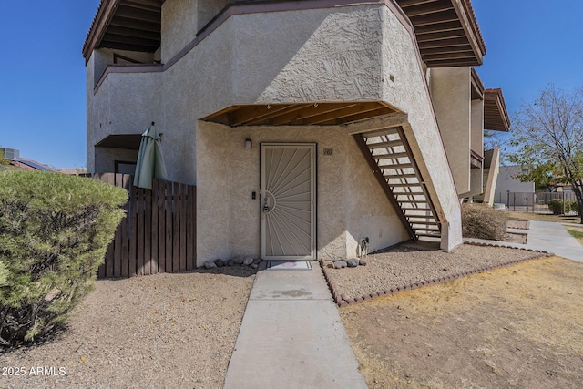 entrance to property with fence and stucco siding