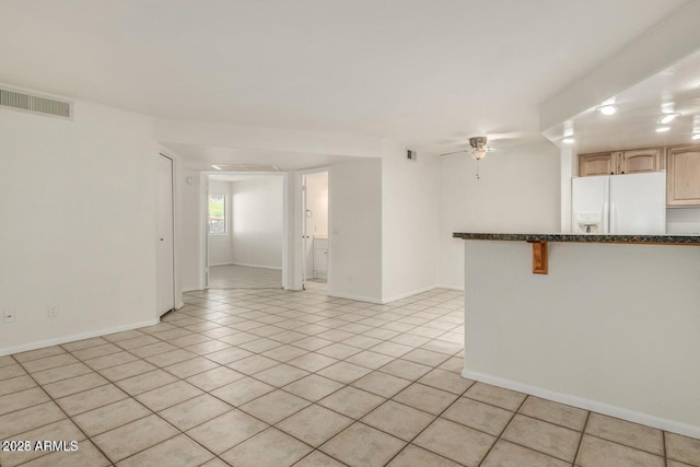 interior space with light tile patterned floors, ceiling fan, visible vents, and baseboards