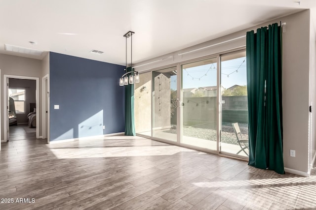 spare room featuring a chandelier and hardwood / wood-style flooring