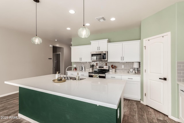 kitchen featuring hanging light fixtures, sink, stainless steel appliances, and a kitchen island with sink