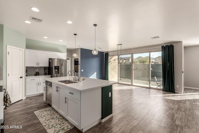 kitchen featuring appliances with stainless steel finishes, a kitchen island with sink, sink, pendant lighting, and white cabinetry