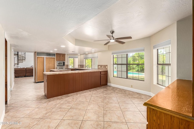 119 E Palomino Dr, Tempe, AZ 85284 - kitchen featuring brown cabinetry, built in appliances, a peninsula, a textured ceiling, and ceiling fan