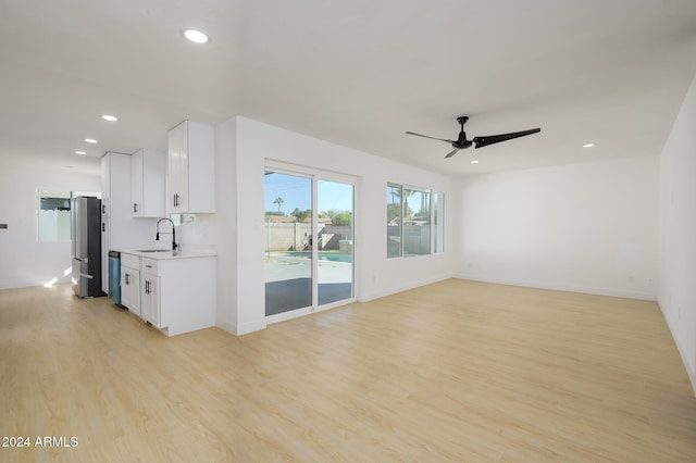 unfurnished living room featuring ceiling fan, sink, and light hardwood / wood-style floors