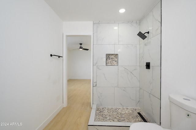 bathroom with hardwood / wood-style flooring, ceiling fan, toilet, and tiled shower