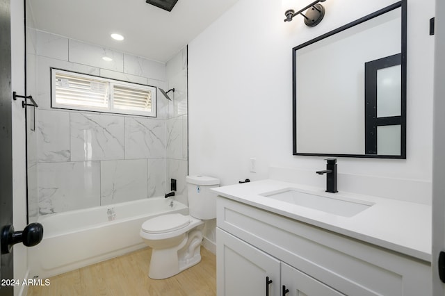 full bathroom featuring hardwood / wood-style floors, tiled shower / bath, toilet, and vanity