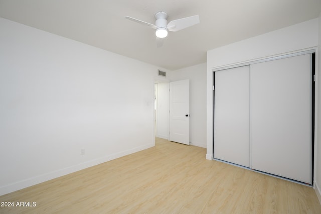 unfurnished bedroom featuring ceiling fan, a closet, and light wood-type flooring