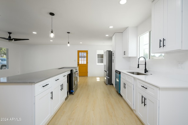 kitchen with a wealth of natural light, white cabinetry, decorative light fixtures, and appliances with stainless steel finishes