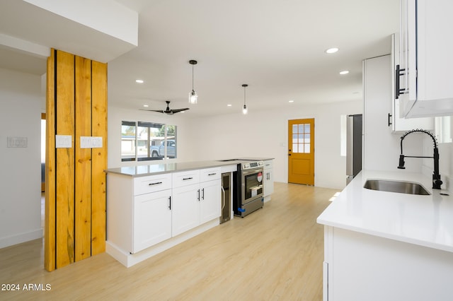 kitchen featuring decorative light fixtures, stainless steel electric range oven, sink, white cabinets, and light hardwood / wood-style flooring