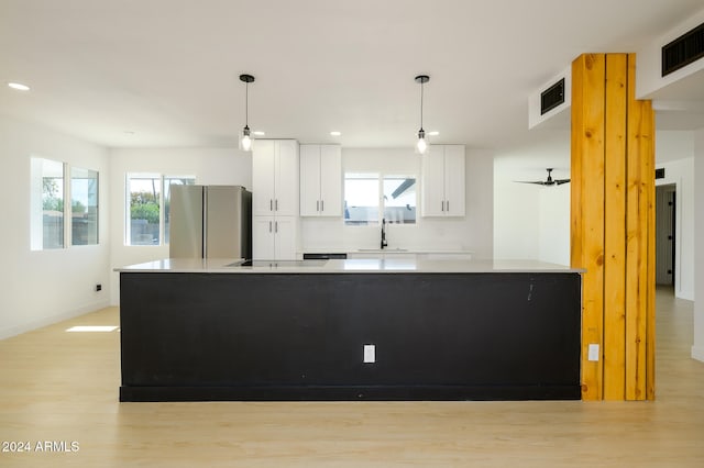 kitchen featuring stainless steel refrigerator, white cabinetry, decorative light fixtures, and a kitchen island