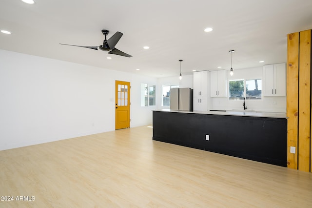 kitchen featuring stainless steel refrigerator, white cabinetry, ceiling fan, decorative light fixtures, and light hardwood / wood-style flooring