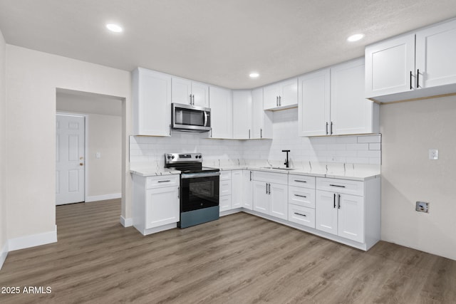 4048 W Granada Rd, Phoenix, AZ 85035 - kitchen with stainless steel appliances, light wood-type flooring, white cabinetry, backsplash, and recessed lighting