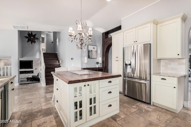 kitchen featuring pendant lighting, stainless steel fridge, butcher block counters, decorative backsplash, and vaulted ceiling