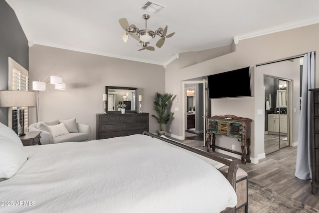 bedroom with lofted ceiling, connected bathroom, crown molding, and hardwood / wood-style flooring