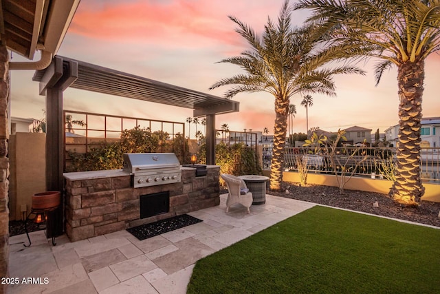 patio terrace at dusk with area for grilling and exterior kitchen