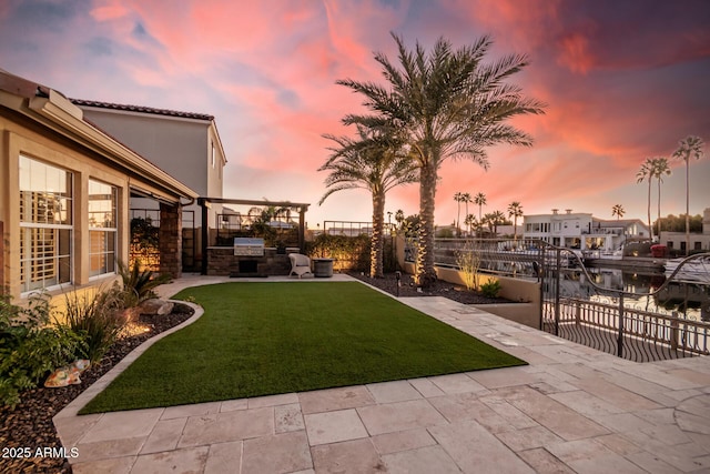 yard at dusk with a patio area and exterior kitchen