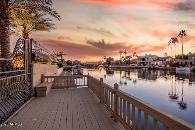 deck at dusk featuring a water view