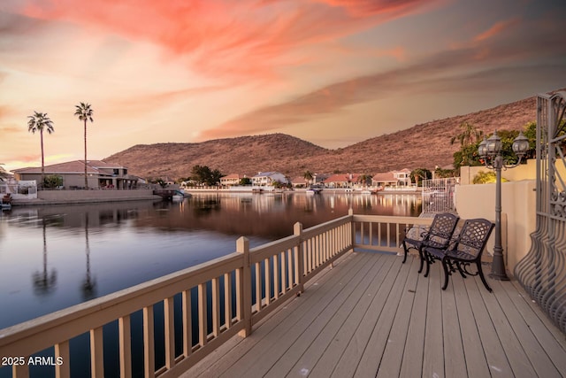 deck at dusk with a water and mountain view