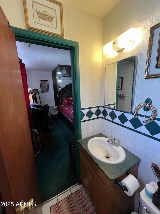 bathroom with vanity, tile patterned flooring, toilet, and tile walls