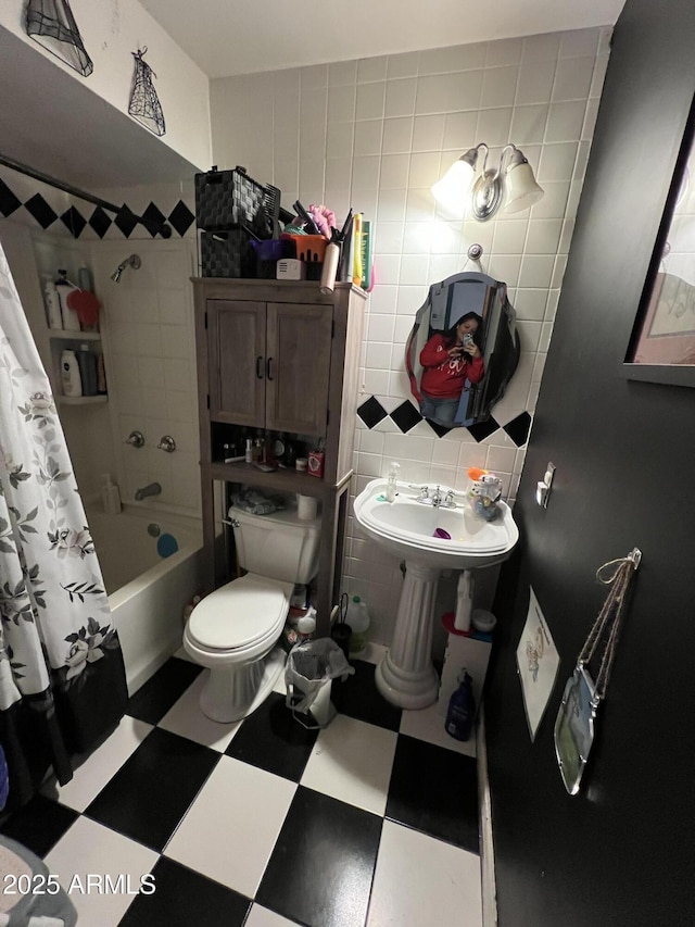 bathroom with tile walls, shower / bath combination with curtain, and toilet