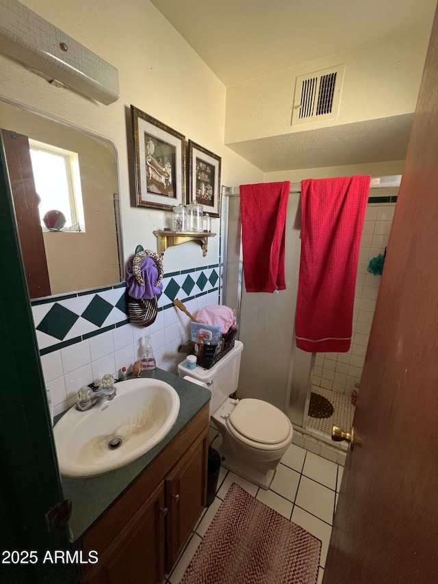 bathroom featuring toilet, a shower, tile walls, vanity, and tile patterned flooring