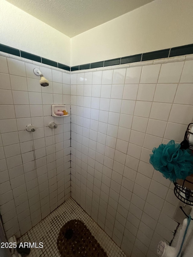 bathroom with a textured ceiling and tiled shower