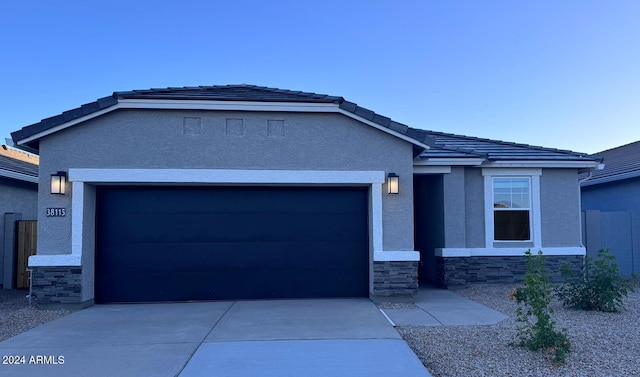 single story home featuring an attached garage, driveway, stone siding, and stucco siding