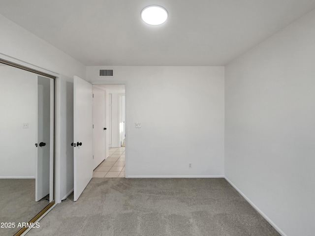 empty room with light tile patterned floors, baseboards, visible vents, and light colored carpet