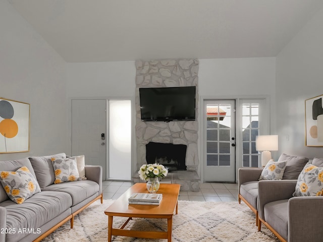 living room featuring a stone fireplace and light tile patterned floors