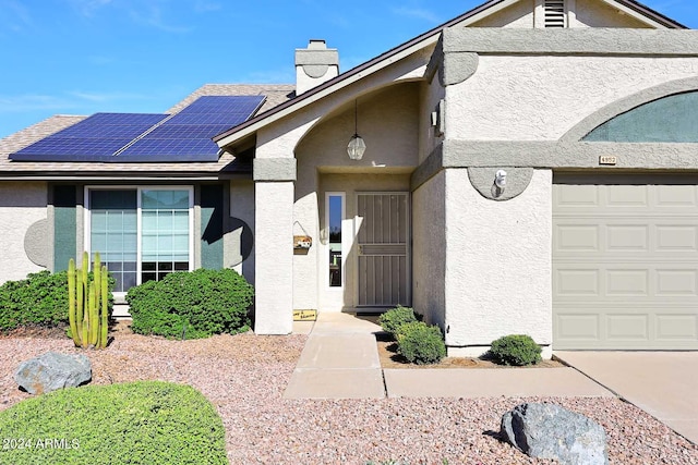 view of exterior entry featuring a garage and solar panels