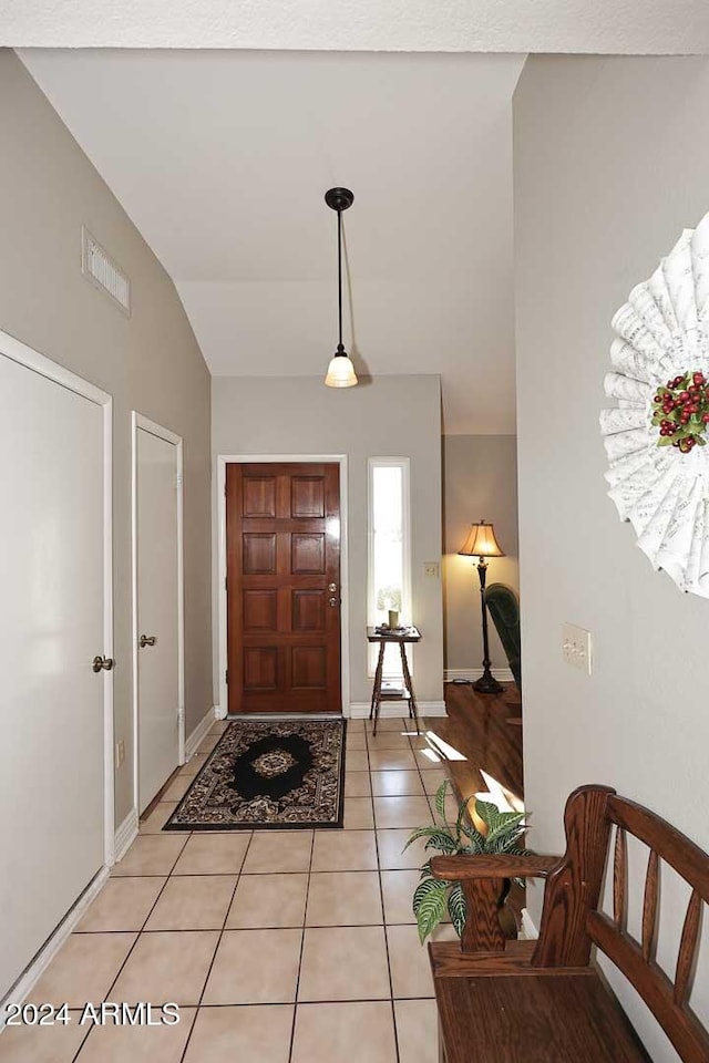 foyer featuring light tile patterned floors and vaulted ceiling