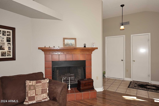 living room featuring hardwood / wood-style flooring, vaulted ceiling, and a tiled fireplace