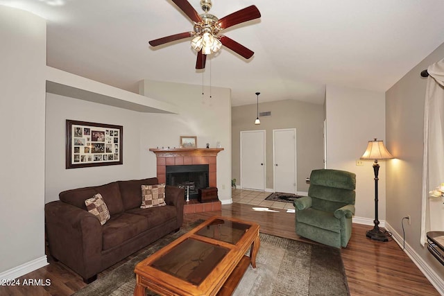 living room with vaulted ceiling, ceiling fan, a tile fireplace, and dark hardwood / wood-style flooring