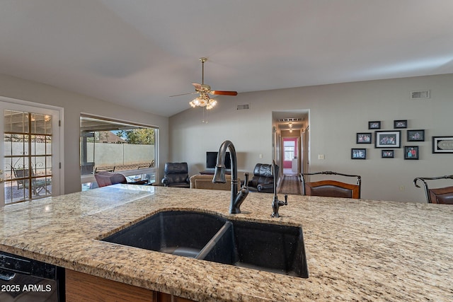 kitchen featuring sink, dishwasher, light stone counters, and lofted ceiling