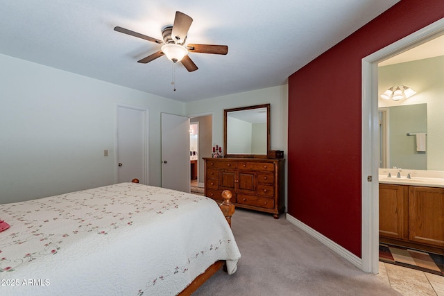 bedroom with sink, light colored carpet, ensuite bath, and ceiling fan