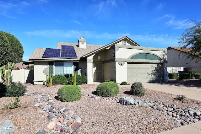 ranch-style house featuring a garage and solar panels