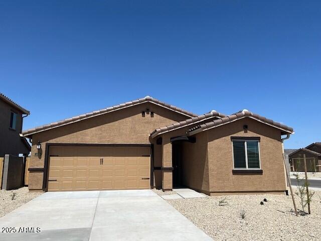 view of front of home featuring a garage, concrete driveway, a tiled roof, and stucco siding