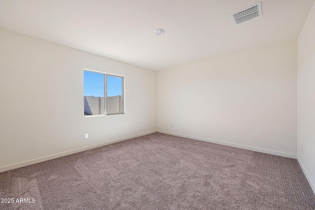 unfurnished room with carpet, visible vents, and baseboards