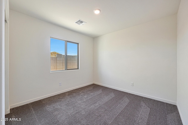 unfurnished room with visible vents, dark carpet, and baseboards