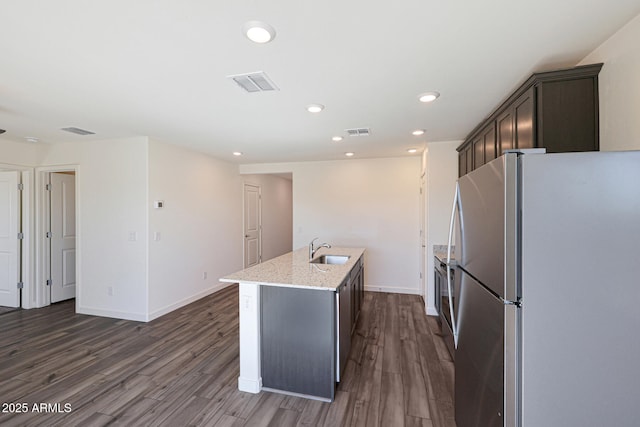 kitchen featuring a center island with sink, visible vents, dark wood-style floors, stainless steel appliances, and a sink