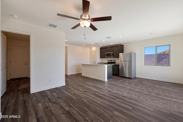 kitchen with dark wood finished floors, a center island with sink, stainless steel appliances, light countertops, and dark brown cabinetry