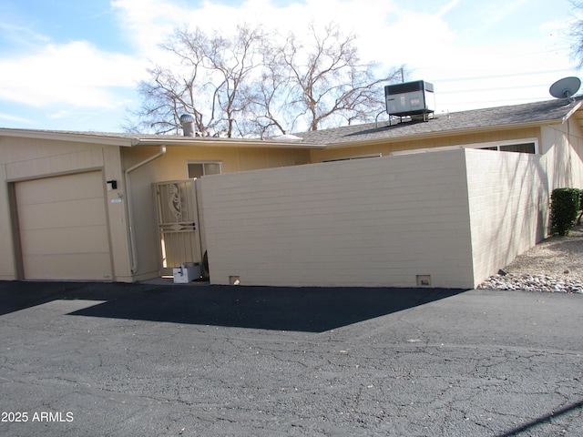 view of side of home featuring brick siding, an attached garage, and cooling unit