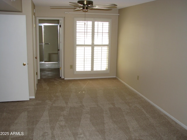 empty room featuring a ceiling fan, light colored carpet, and baseboards