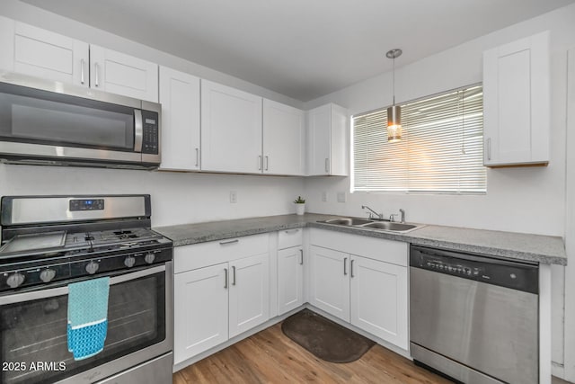 715 W Cinnabar Ave, Phoenix, AZ 85021 - kitchen with white cabinets, appliances with stainless steel finishes, wood finished floors, a sink, and hanging light fixtures
