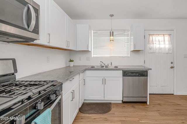 715 W Cinnabar Ave, Phoenix, AZ 85021 - kitchen featuring hanging light fixtures, white cabinets, a sink, light wood finished floors, and stainless steel appliances