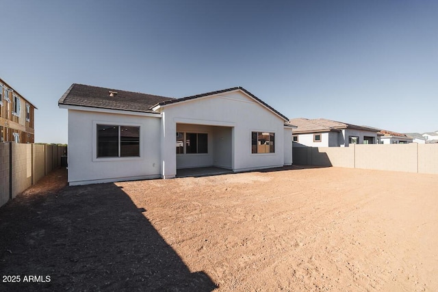 rear view of house with a fenced backyard and stucco siding