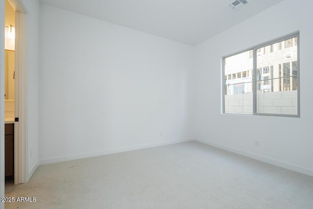 spare room with visible vents, light carpet, and baseboards