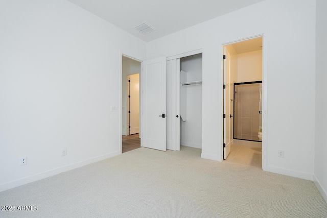 unfurnished bedroom with ensuite bath, visible vents, carpet flooring, and baseboards
