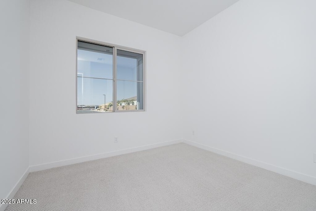 carpeted spare room featuring baseboards