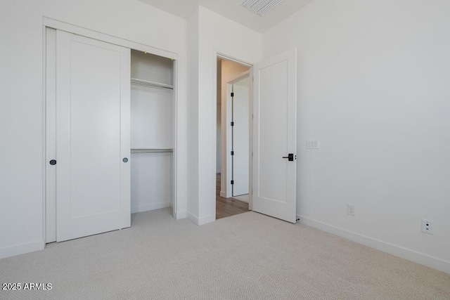 unfurnished bedroom with baseboards, visible vents, a closet, and carpet