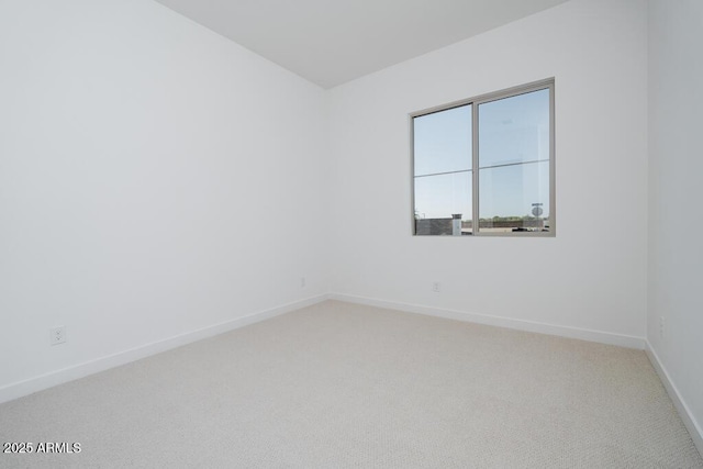 empty room featuring baseboards and light carpet